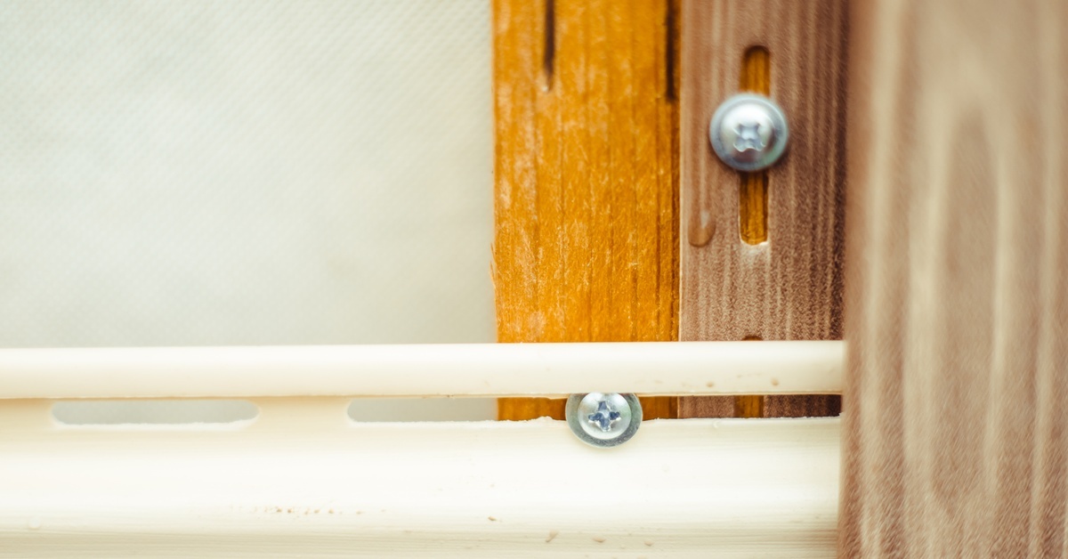 An extreme close-up of where vinyl siding meets a wall during its installation. Two silver nails are visible.