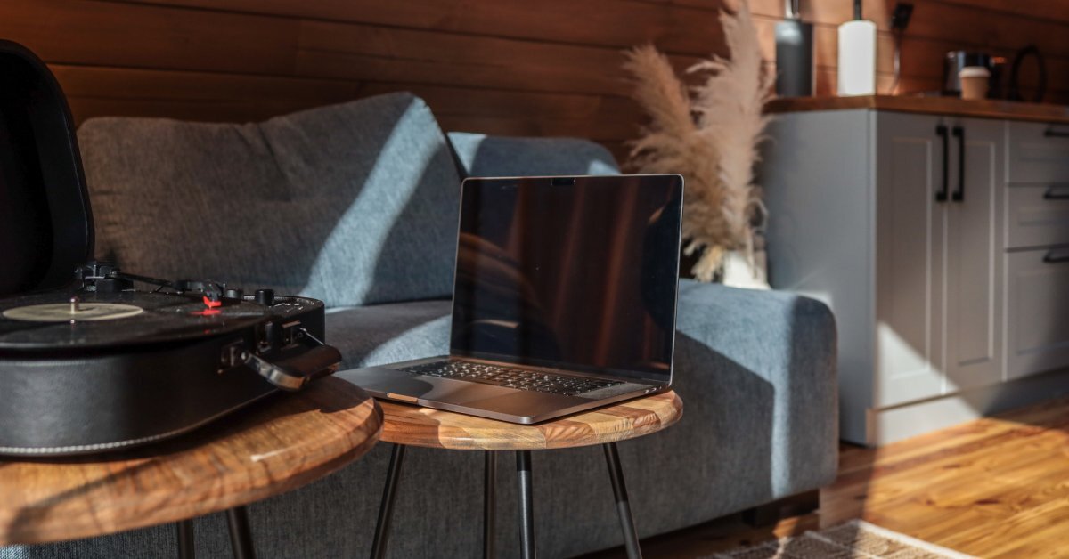 The interior of a cozy cabin living room with a sofa and coffee table. Wood-like siding covers the back wall.